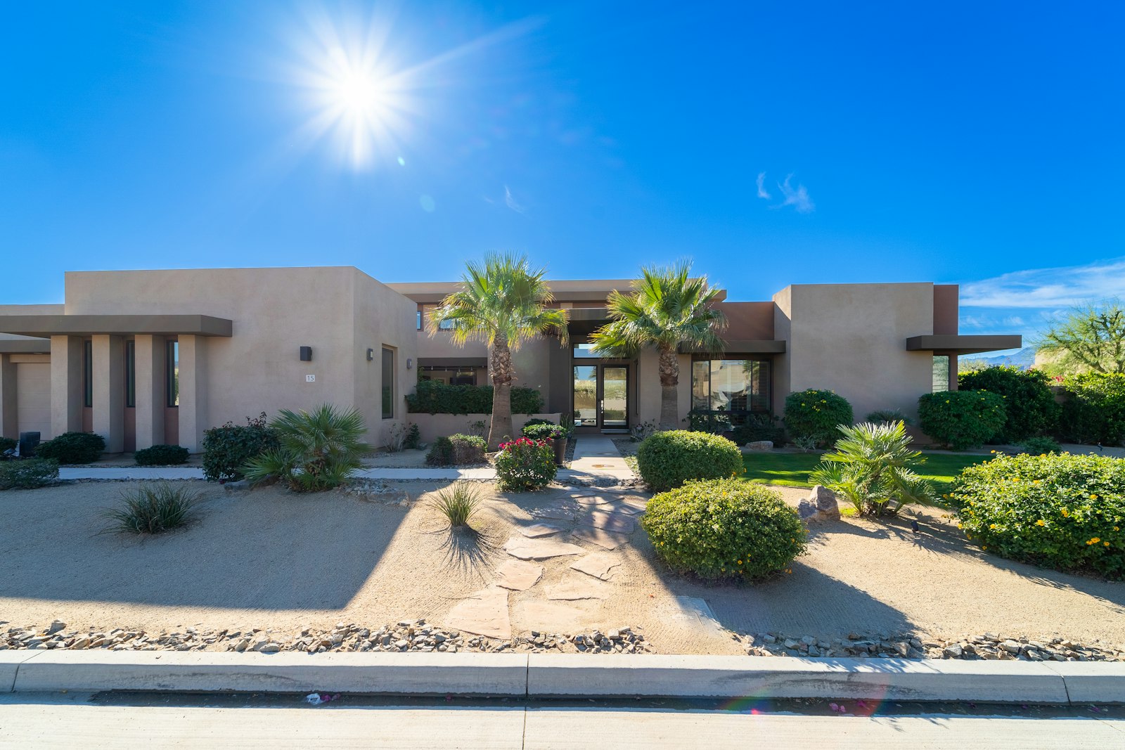 Single-level desert home with palm trees and desert landscaping