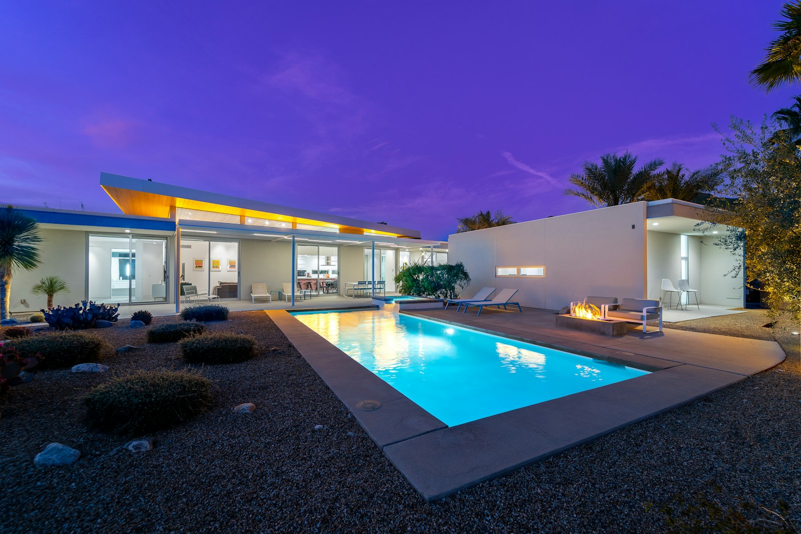 Modern home with an illuminated pool at dusk